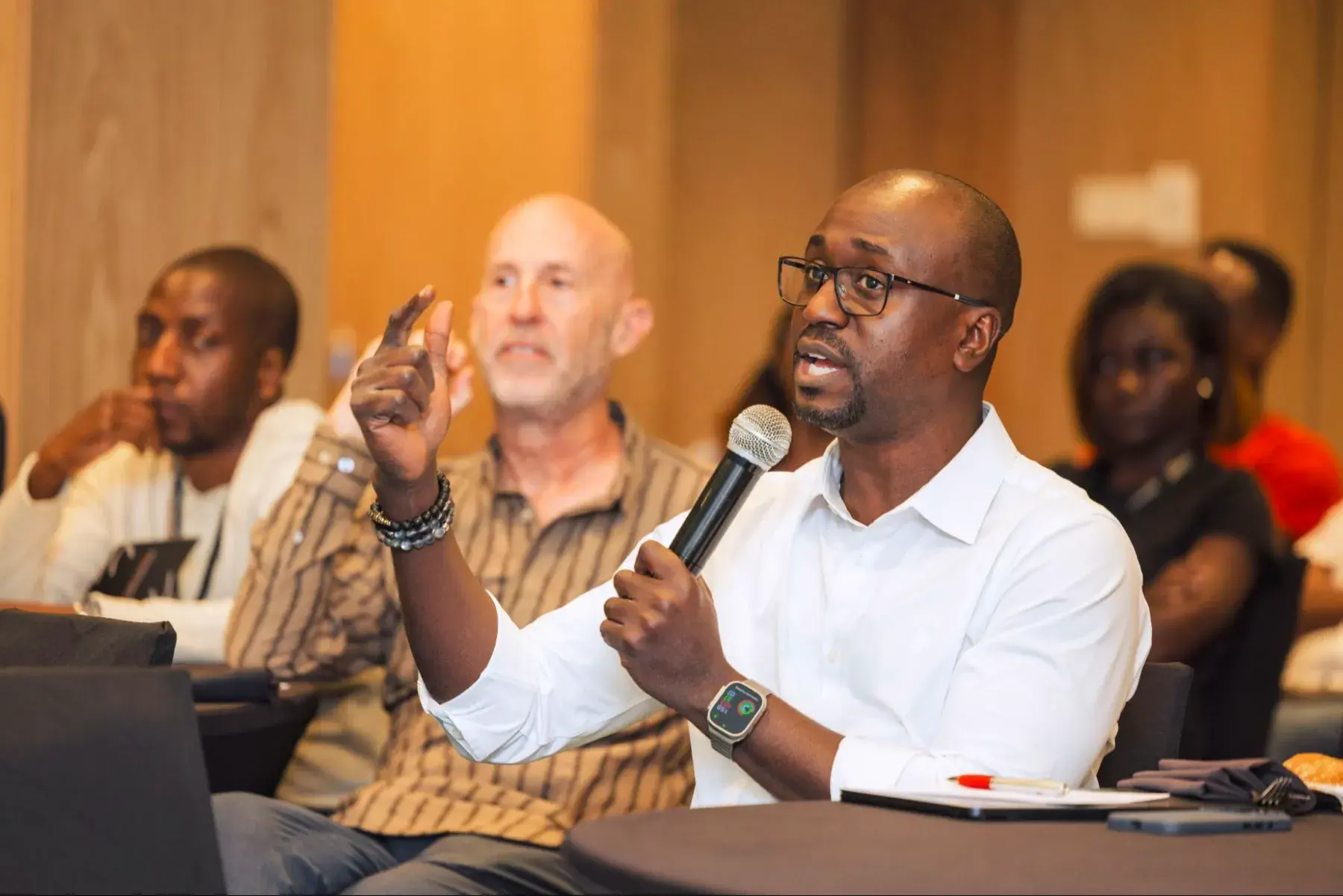 A speaker taking questions from the audience at a conference table